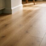 Installed laminate wood flooring in a sunlit modern kitchen with warm honey-toned planks visible from living area